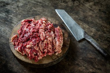 Parçalanmış ham sığır eti kesme tahtası üzerinde bıçak ile.