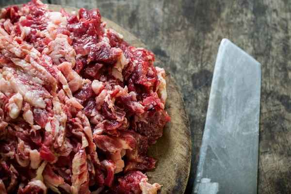 Parçalanmış ham sığır eti kesme tahtası üzerinde bıçak ile.