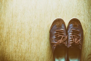 Bir ahşap zemin, vintage renk tonu üstten görünüm üzerinde eski kahverengi spor ayakkabı.