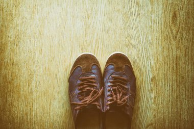 Bir ahşap zemin, vintage renk tonu üstten görünüm üzerinde eski kahverengi spor ayakkabı.