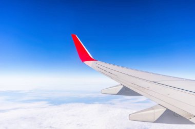 Bulutların üstünde mavi gökyüzü üzerinde uçak sol kanadının penceresinden görüntülemek.