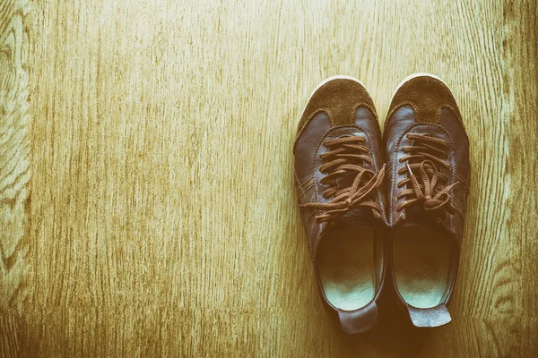 Bir ahşap zemin, vintage renk tonu üstten görünüm üzerinde eski kahverengi spor ayakkabı.