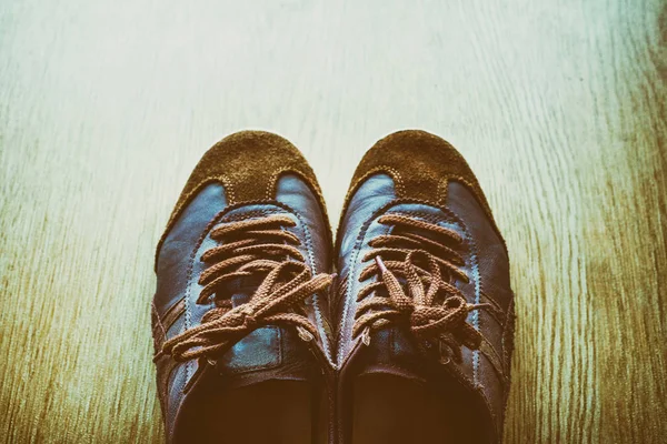 Bir ahşap zemin, vintage renk tonu üstten görünüm üzerinde eski kahverengi spor ayakkabı.