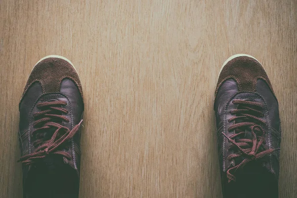 Bir ahşap zemin, vintage açık renk tonu üstten görünüm üzerinde eski kahverengi spor ayakkabı.
