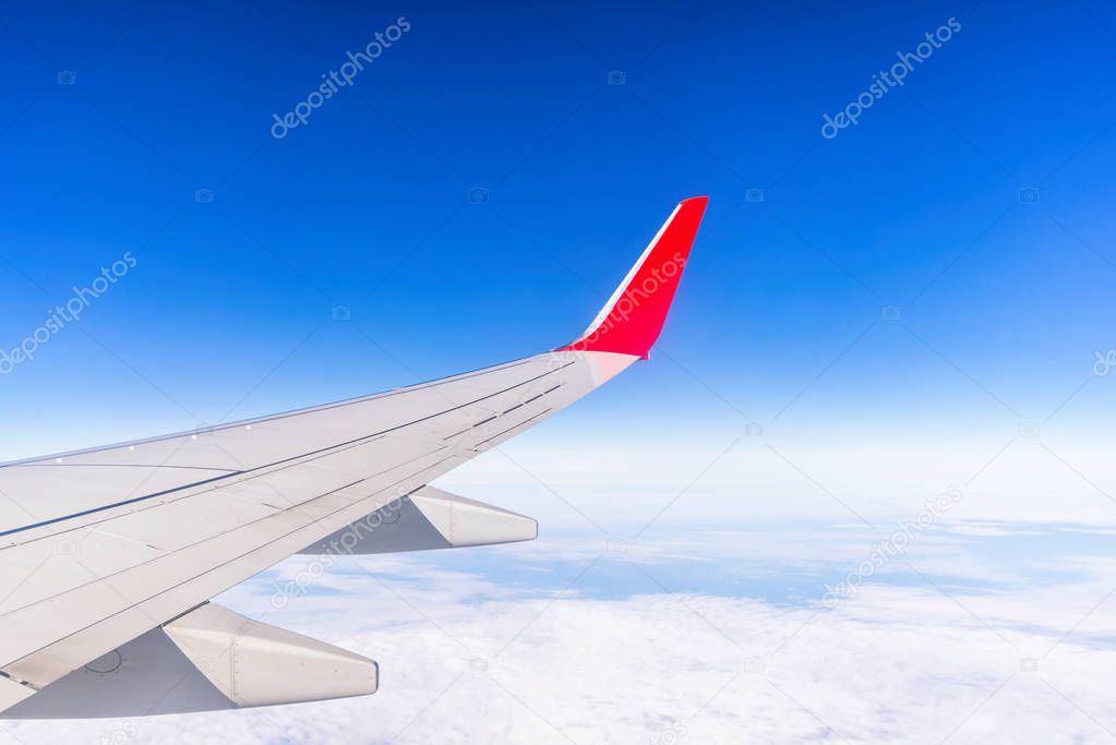 View from window of aircraft right wing on the blue sky above the clouds.