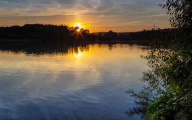 İngiltere'de küçük bir göl üzerinde günbatımı.