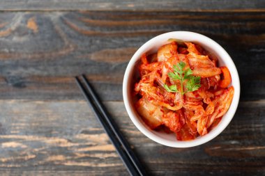 Ahşap arka plan, üstten görünüm, Kore yemeği yemek için yemek çubukları ile bir kase kimchi lahana