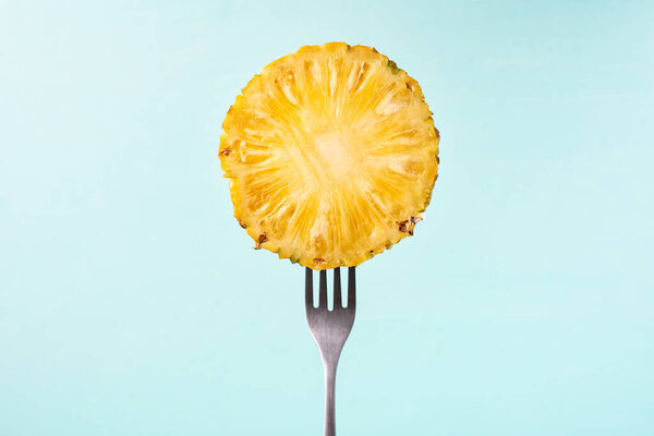 Half of pineapple on fork for eating, tropical fruit