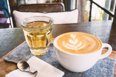 Latte sanat kahve ve kahve dükkanında ahşap plaka üzerinde sıcak çay fincan