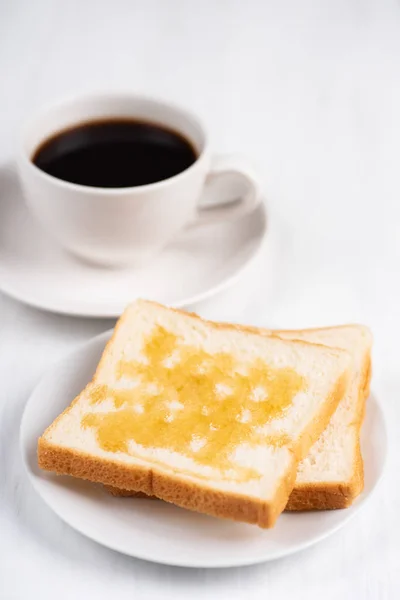 蜂蜜のトッピングが付いてスライスしたパンとコーヒー カップの黒白いテーブル おいしい朝食 — ストック写真