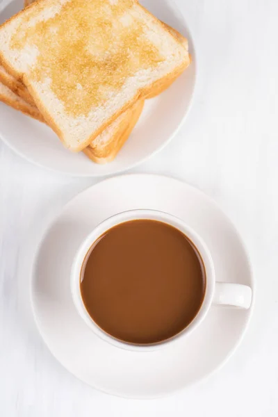 Cup of coffee and sliced bread with honey topping on white table