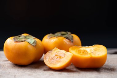 Trabzon hurması meyve ahşap ve siyah arka plan üzerinde sağlıklı meyve dilimlenmiş