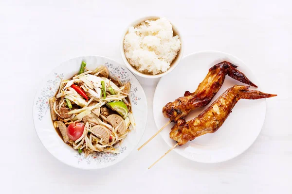 Thai food, spicy papaya salad with steamed pork sausage and grilled chicken wing  and sticky rice