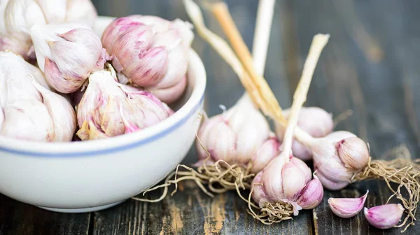 Fresh garlic on wooden and bowl, close up — Stock Photo, Image