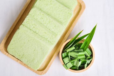 Ahşap tabak ve pandan yaprağı üzerinde dilimlenmiş pandan ekmek, üst görünümü