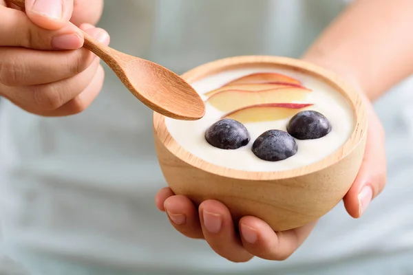 Eating yoghurt with sliced apple and grape in a bowl — Stock Photo, Image