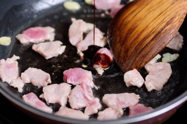 Sıcak bir tavada soya sosu dökme ve domuz eti ile kızarmış karıştırın