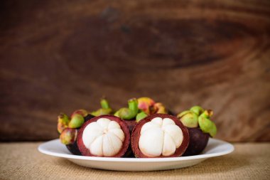 Beyaz tabakta taze mangosteen meyvesi ve ahşap arka plan, Tayland meyvesi.