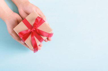 Pastel arka planda kırmızı kurdeleli hediye paketi. Özel bir gün için hediye.