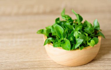 Tahta arka planda bir kasede taze su teresi.