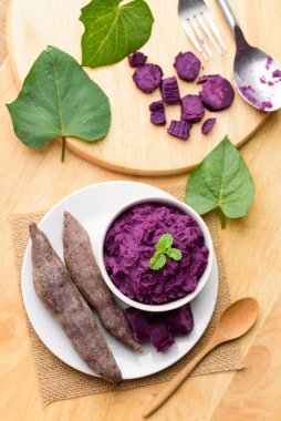 Tahta masadaki kaşıkla bir kasede mor patates püresi, sağlıklı yiyecekler.