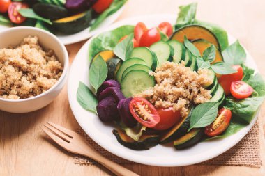 Sebzeli salata kinoası tohumu (marul, salatalık, domates, balkabağı, tatlı patates ve fesleğen yaprağı), sağlıklı vejetaryen yemeği