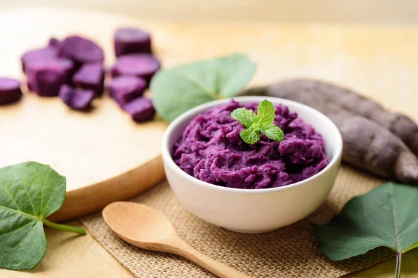 Tahta masadaki kaşıkla bir kasede mor patates püresi, sağlıklı yiyecekler.