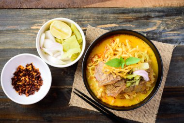 Kuzey Tayland yemeği (Khao Soi), baharatlı körili şehriye çorbası kasede sığır eti, kızarmış yumurta eriştesi, turşulu hardal, arpacık soğanı, limon ve yağda kızartılmış kırmızı biber.