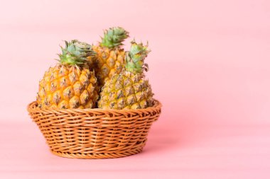 Pastel pembe arka planda bir sepette taze ananas meyvesi, tropikal meyve.