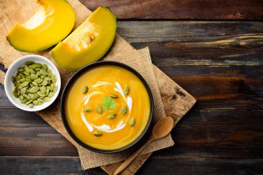 Kasede balkabağı çorbası ve ahşap masada kabak tohumları.