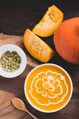 Kabak çorbası içinde tohumlar ve ahşap zemin üzerinde taze balkabağı