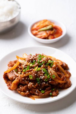Beyaz arka planda pişmiş pirinç ve kimchi ile Kore usulü kızarmış baharatlı domuz eti (Bulgogi).