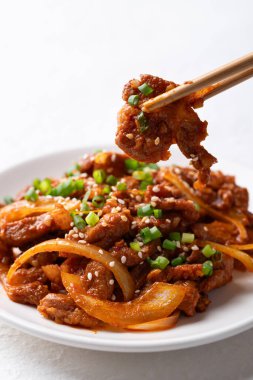 Kore usulü kızarmış baharatlı domuz eti (Bulgogi) ve yemek çubuğu.