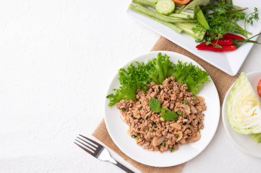Yerel Tayland yemekleri, baharatlı domuz salatası (Larb Moo) beyaz arka planda taze sebzelerle yemek