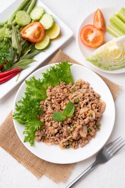 Yerel Tayland yemekleri, baharatlı domuz salatası (Larb Moo) beyaz arka planda taze sebzelerle yemek
