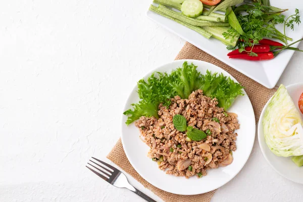 Yerel Tayland yemekleri, baharatlı domuz salatası (Larb Moo) beyaz arka planda taze sebzelerle yemek