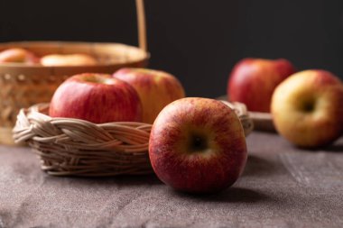 Siyah arkaplanlı kahverengi kumaş üzerinde kırmızı elma (Envy apple) sepeti