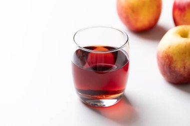 Beyaz arka planda kırmızı elma meyveli bir bardak elma şarabı.