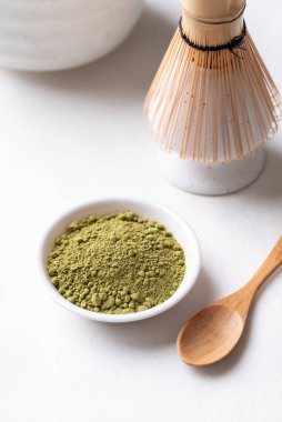 Bambu çırpmalı kibrit yeşili çay tozu ve beyaz arka planda kase.