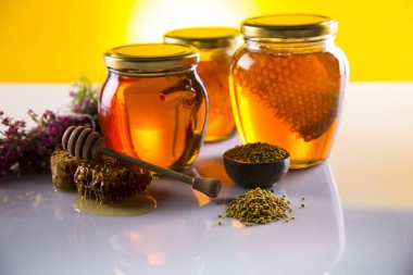 Honey in jar with honey dipper on wooden background clipart