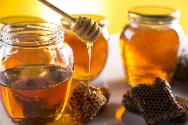 Мед в банке с медом ковша на деревянном фоне
