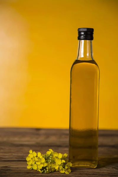 Rapeseed flowers and rapeseed oil in a bottle on the table