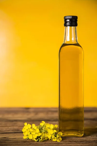 Rapeseed flowers and rapeseed oil in a bottle on the table