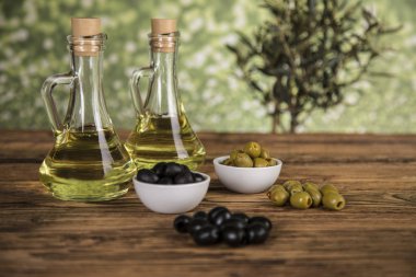 Ahşap tabonda zeytinyağı, zeytin ağacı ve yeşil ve siyah zeytin