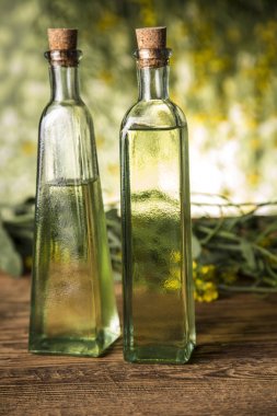 Masadaki şişede kolza tohumu çiçeği ve yağ var.