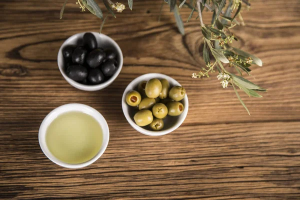 Olive oil, olive tree and green and black olives on a wooden tab