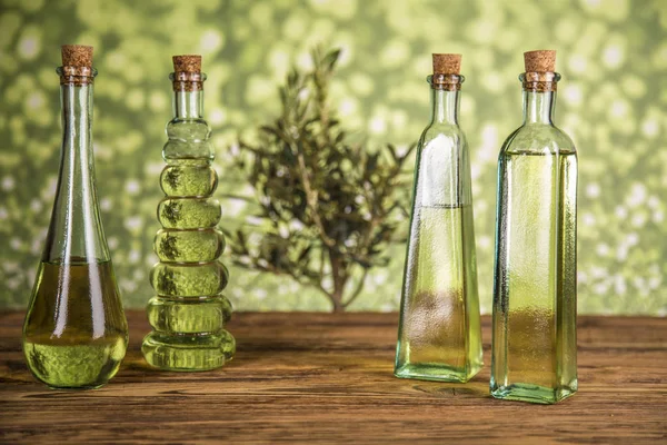 Olivo y botellas con aceite, aceitunas sobre una mesa de madera — Foto de Stock