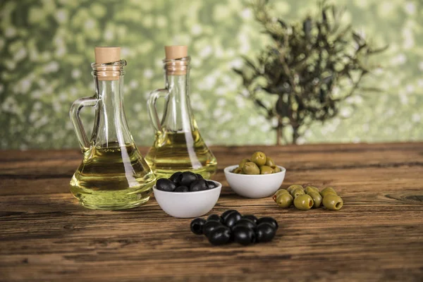 Olive oil, olive tree and green and black olives on a wooden tab — Stock Photo, Image