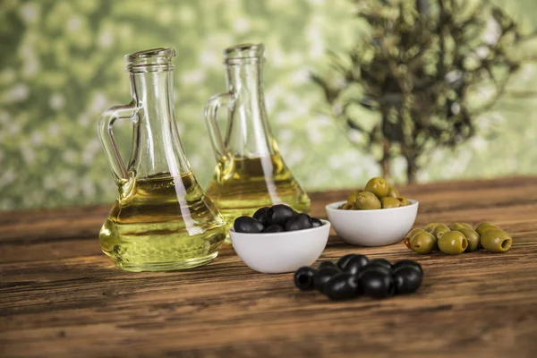 Olive oil, olive tree and green and black olives on a wooden tab