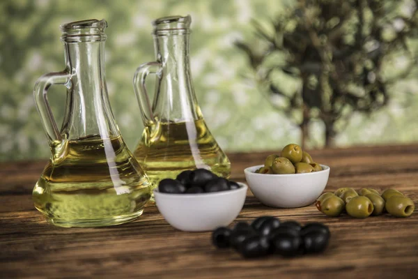 Olive oil, olive tree and green and black olives on a wooden tab